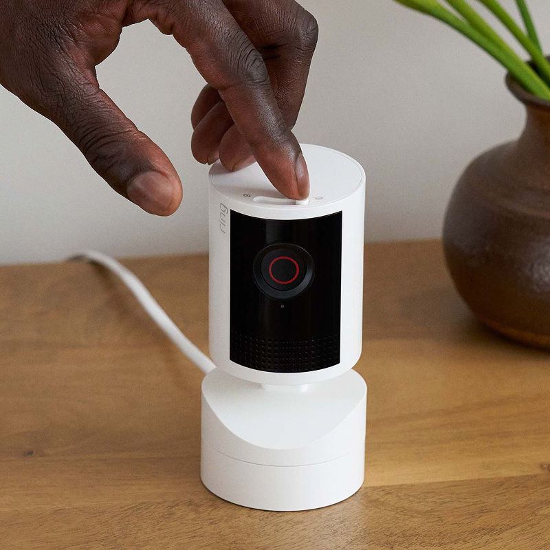 Primer plano de Pan-Tilt Indoor Camera 2K blanca mientras una persona desliza la cubierta de privacidad integrada.