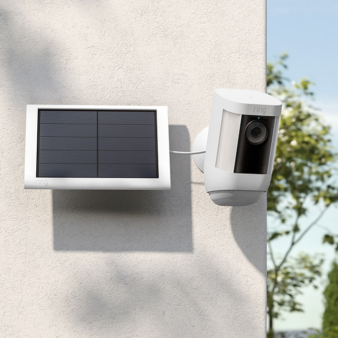 Ring Spotlight Cam Pro connectée au panneau solaire, fixée au mur pour une surveillance continue.