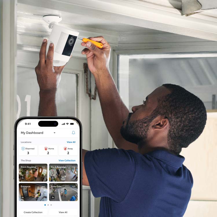 Una persona installa una telecamera Ring bianca sopra una porta usando un cacciavite