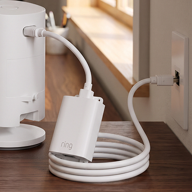 PoE+ to USB-C Indoor Adapter connected to a Ring Indoor Camera and Ethernet wall port, with a coiled cable on a wooden table