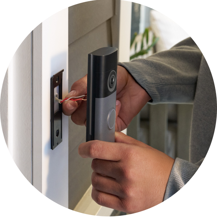 Close-up of a person holding exposed wires from a door post to connect them to the Wired Video Doorbell (2nd Gen).