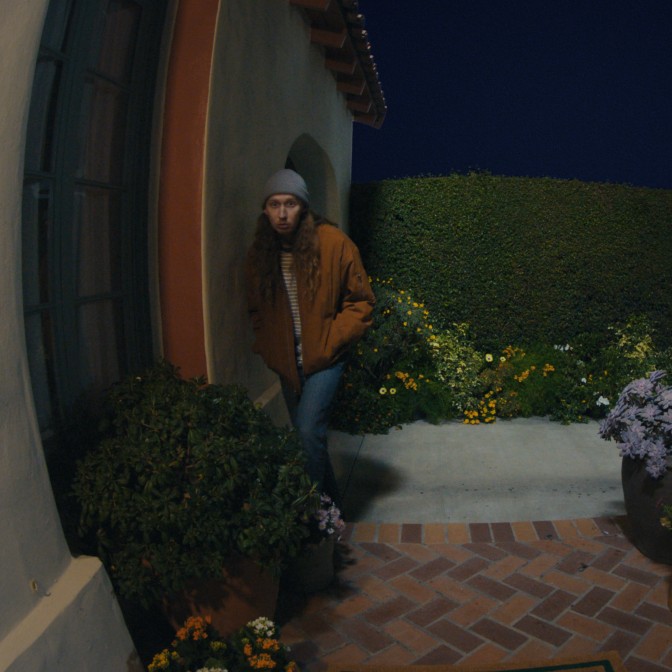 A dark image of a person sneaking up towards a house