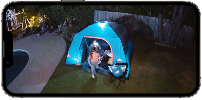 Ring Spotlight Cam Plus Battery filme une famille qui campe dans le jardin, montrant la vision nocturne en couleur.