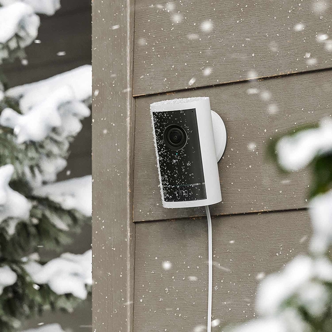 Witte Outdoor Camera Pro in de sneeuw, bevestigd aan de zijkant van een huis