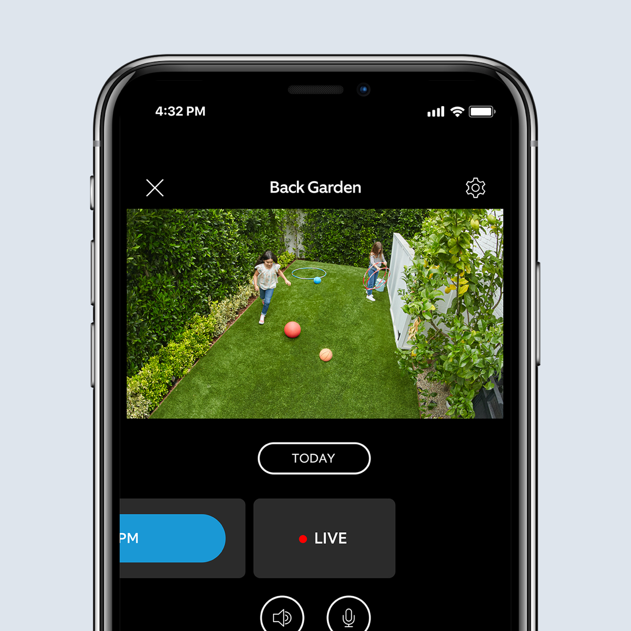 Smartphone screen showing live Ring app video of children playing with balls in a back garden.
