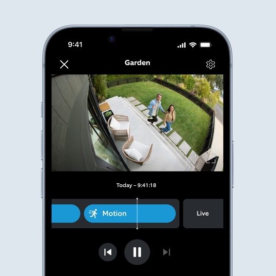 Phone shows wide-angle garden view in Ring app with two visitors, motion event, and live Two-Way Talk controls.