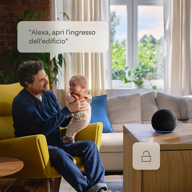 Un papà che tiene il suo bambino e parla con Alexa.