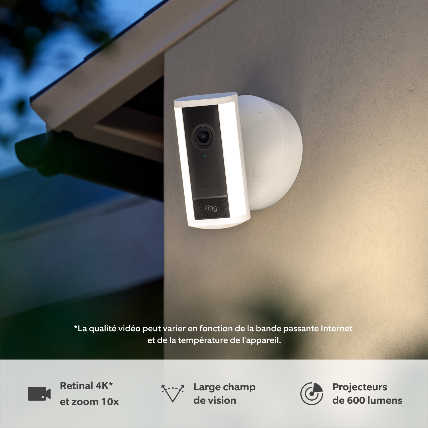 Caméra Spotlight Pro filaire (nouvelle génération) (for Spotlight Cam Pro Wired (2nd Gen)) - Une caméra Spotlight Pro Ring (nouvelle génération) blanche fixée à un mur au crépuscule sous la pluie avec spots LED intégrés illuminés