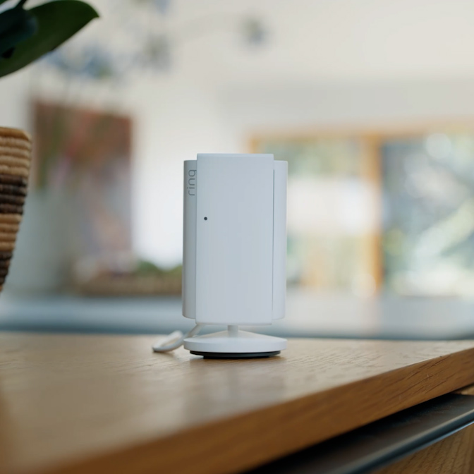 Close-up of hands closing the removable Manual Lens Cover on a white Indoor Cam Plus.