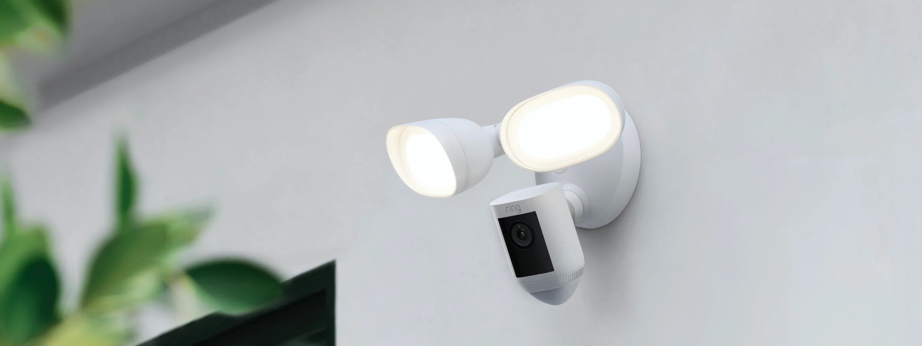 Ring Floodlight Cam Wired Pro montada en pared exterior con luces LED iluminadas para vigilancia exterior