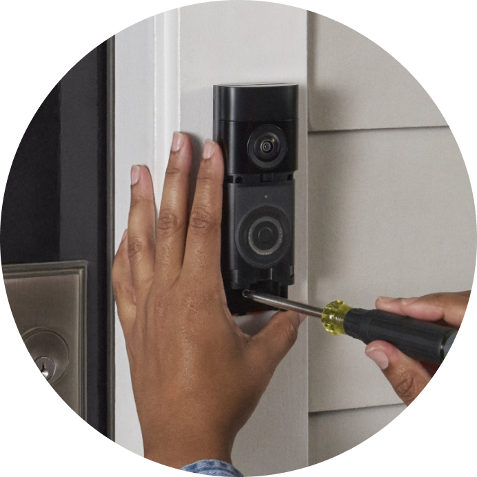 Close-up of a person screwing the mounting bracket of the Battery Video Doorbell Plus onto a door post and clicking the device into place