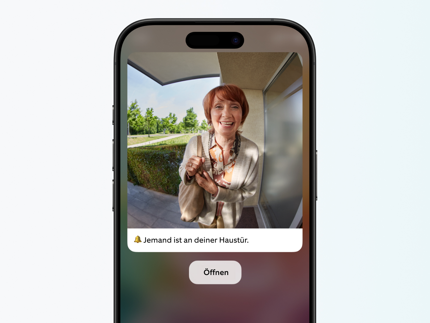 Smartphone-Bildschirm der Ring App zeigt eine winkende Frau an der Haustür mit der Benachrichtigung 