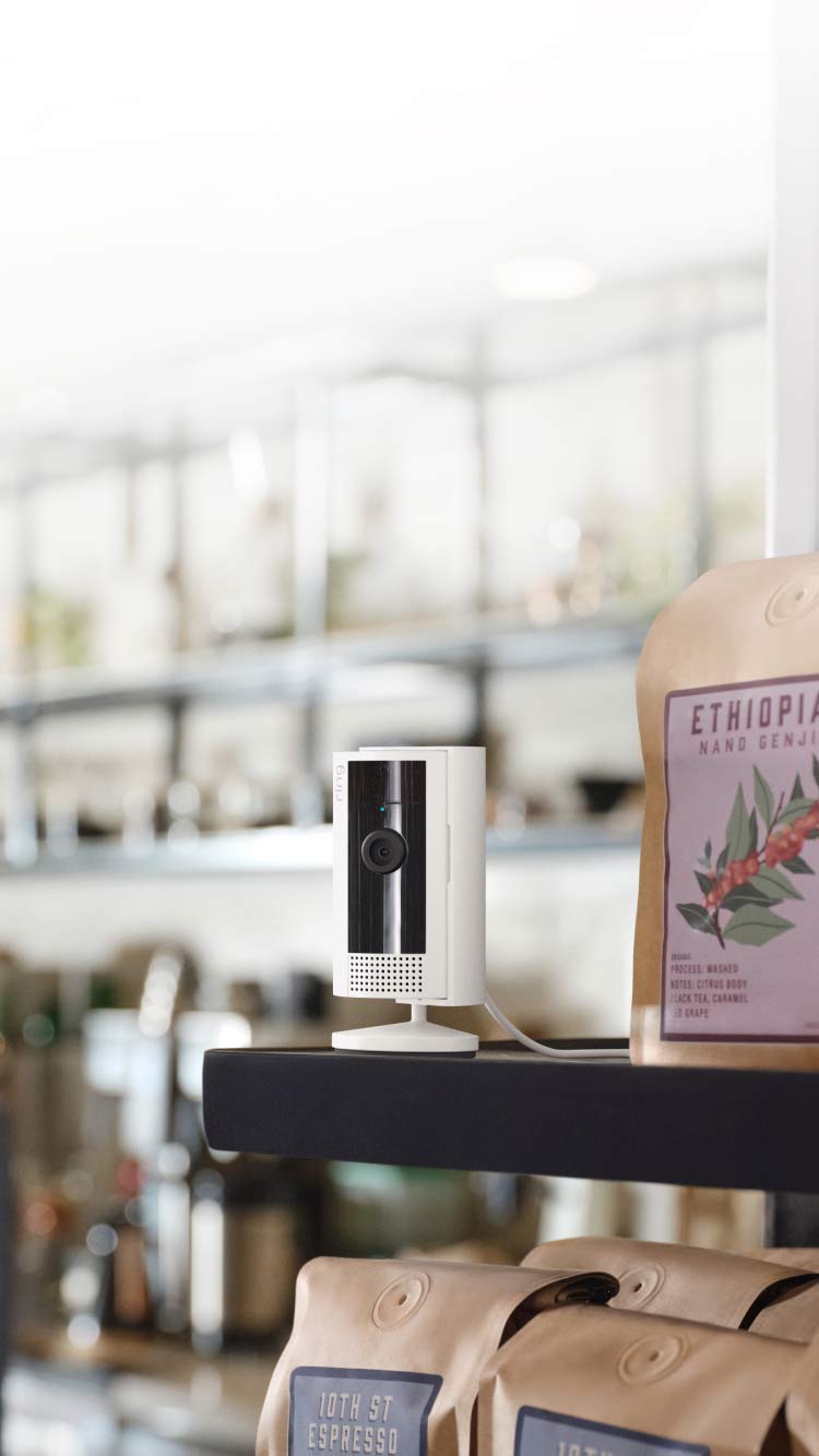 Una Ring Indoor Camera bianca montata su un bancone in un negozio