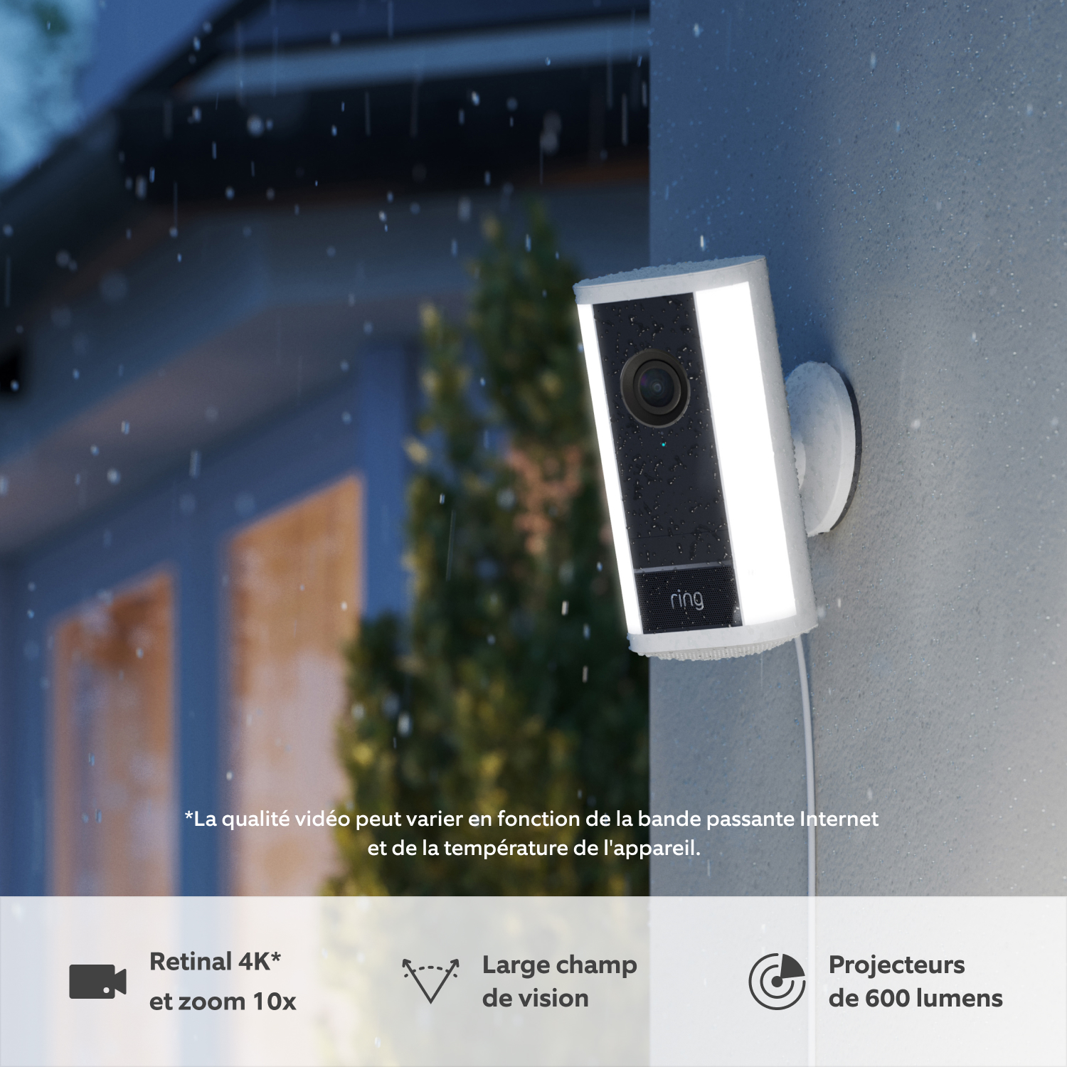 Caméra Spotlight Pro (nouvelle génération) avec adaptateur secteur (for Spotlight Cam Pro Plug-In (2e génération)) - Une caméra Spotlight Pro Ring (nouvelle génération) blanche fixée à un mur, au crépuscule et sous la pluie, avec projecteurs LED intégrés allumés