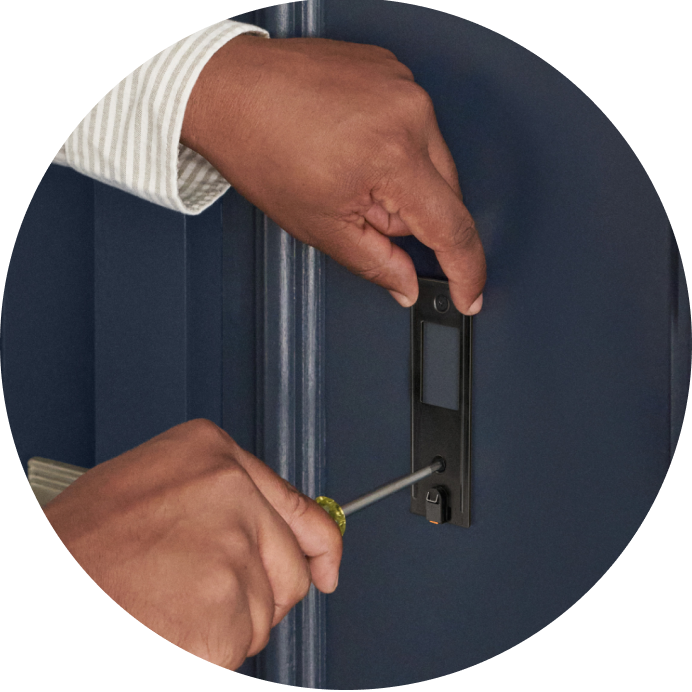 Close-up of a person screwing the mounting bracket of the Battery Video Doorbell onto a surface next to a door