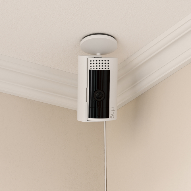 Ring Indoor Camera mounted upside down on ceiling corner with swivel base for flexible overhead viewing.