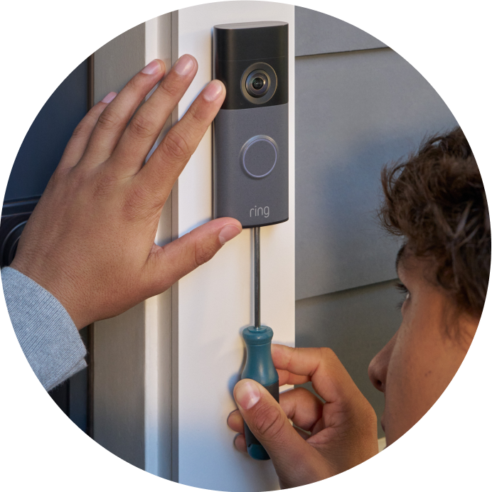 Close-up of a person screwing a Wired Video Doorbell (2nd Gen) to the mounting plate on a door post.
