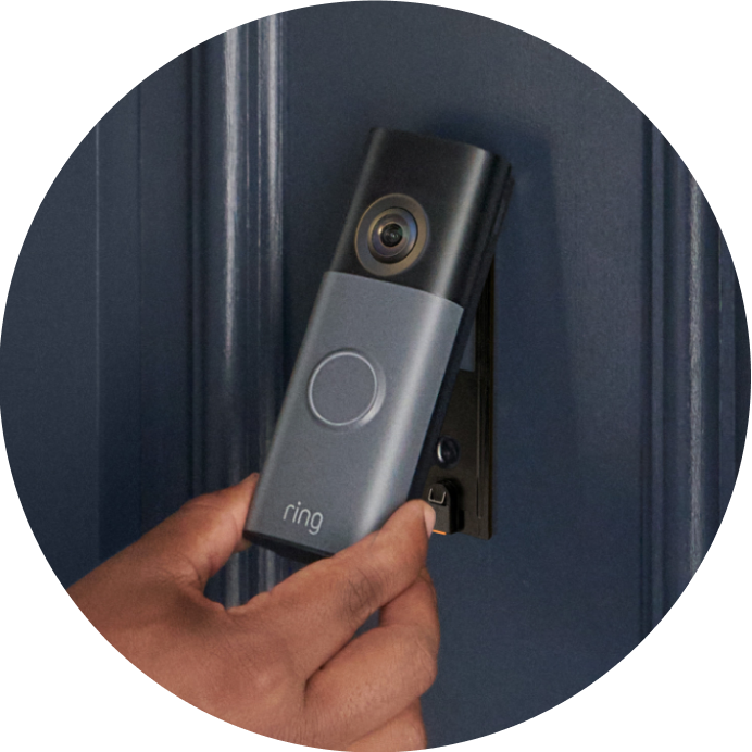 Close-up of a person placing the Battery Video Doorbell onto its mounting bracket on the wall