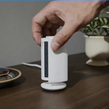 Ring Indoor Camera 4K in white on a circular base, placed on a light wooden bench in a bright, modern home interior.