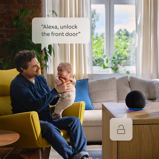 A dad holding his kid and talking to Alexa.