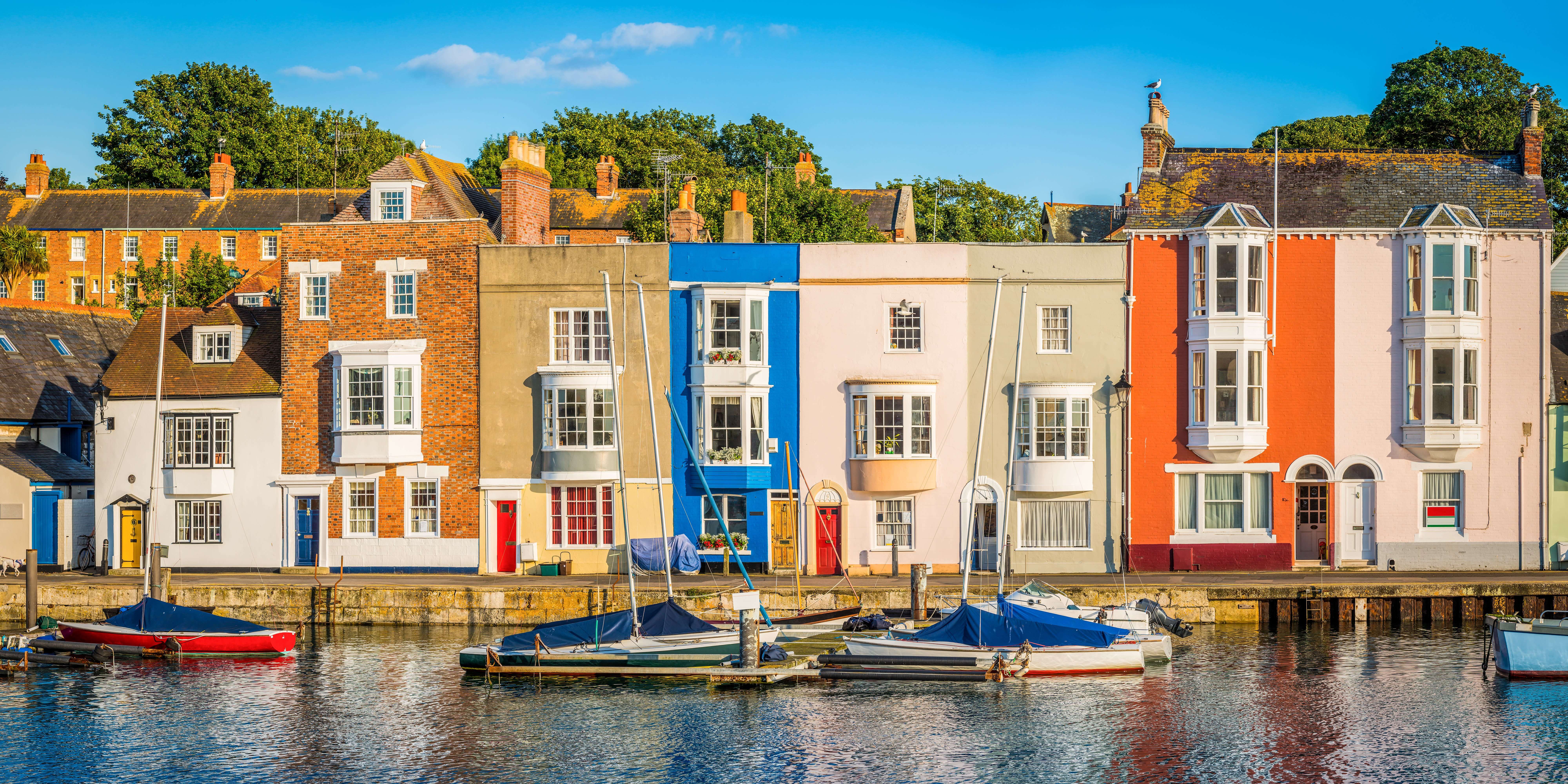 A row of colourful terraced houses in front of water, sunny day