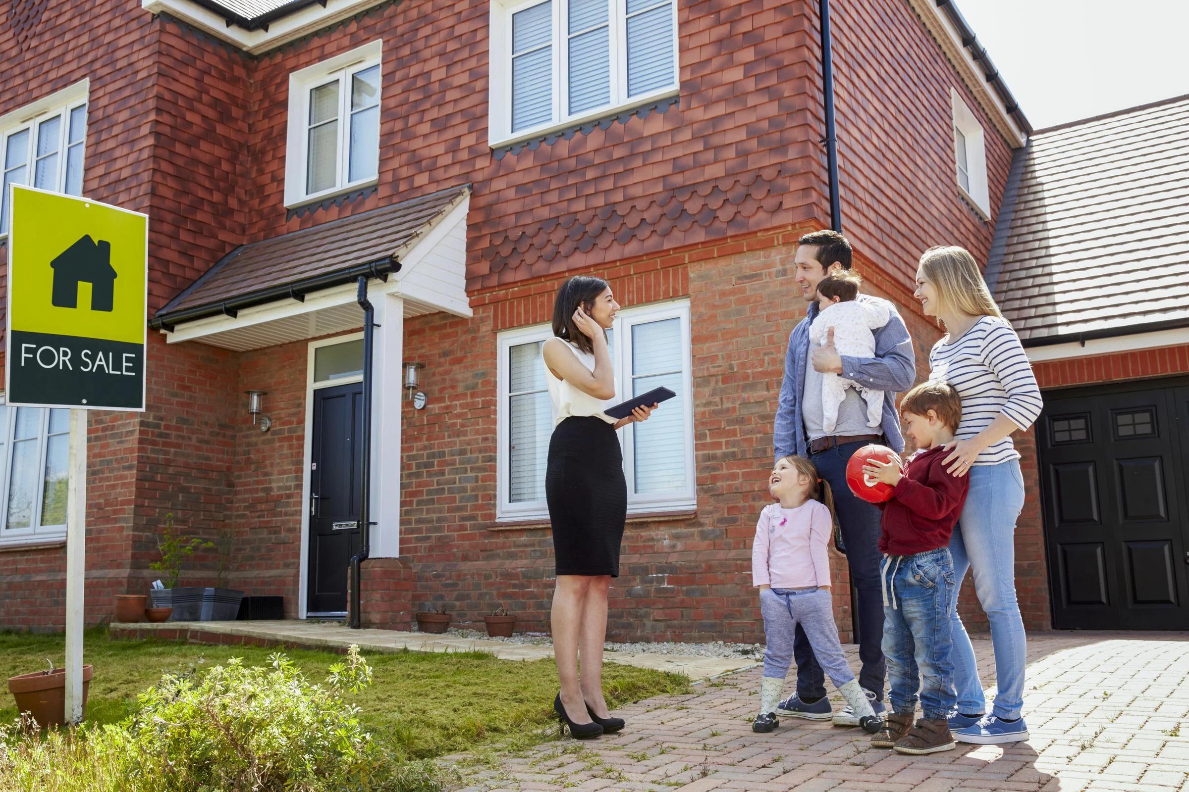 Family speaking to an agent outside their house for sale