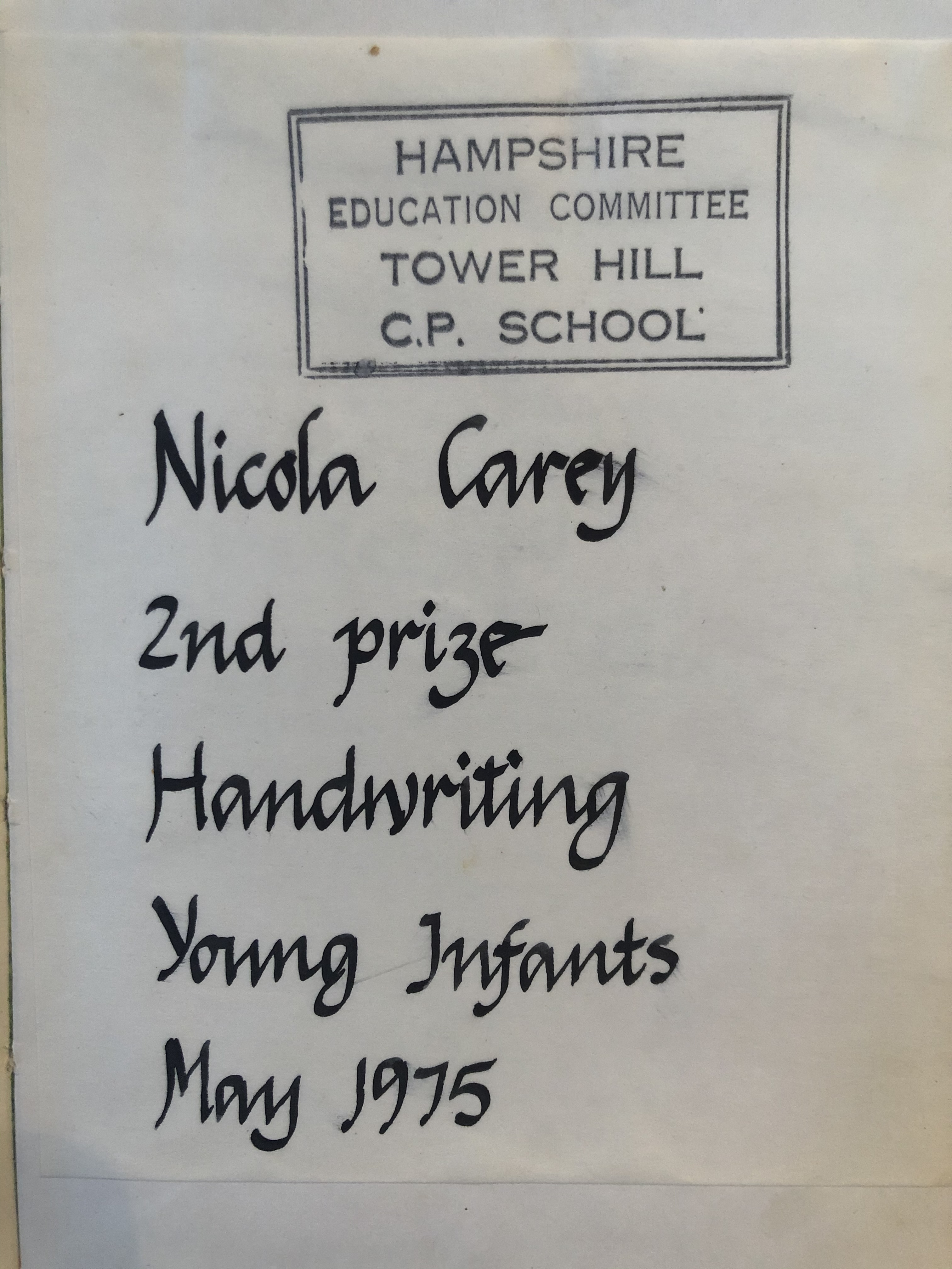 School prize book plate with handwritten name 'Nicola Carey' and text '2nd prize Handwriting, Young Infants, May 1975'.