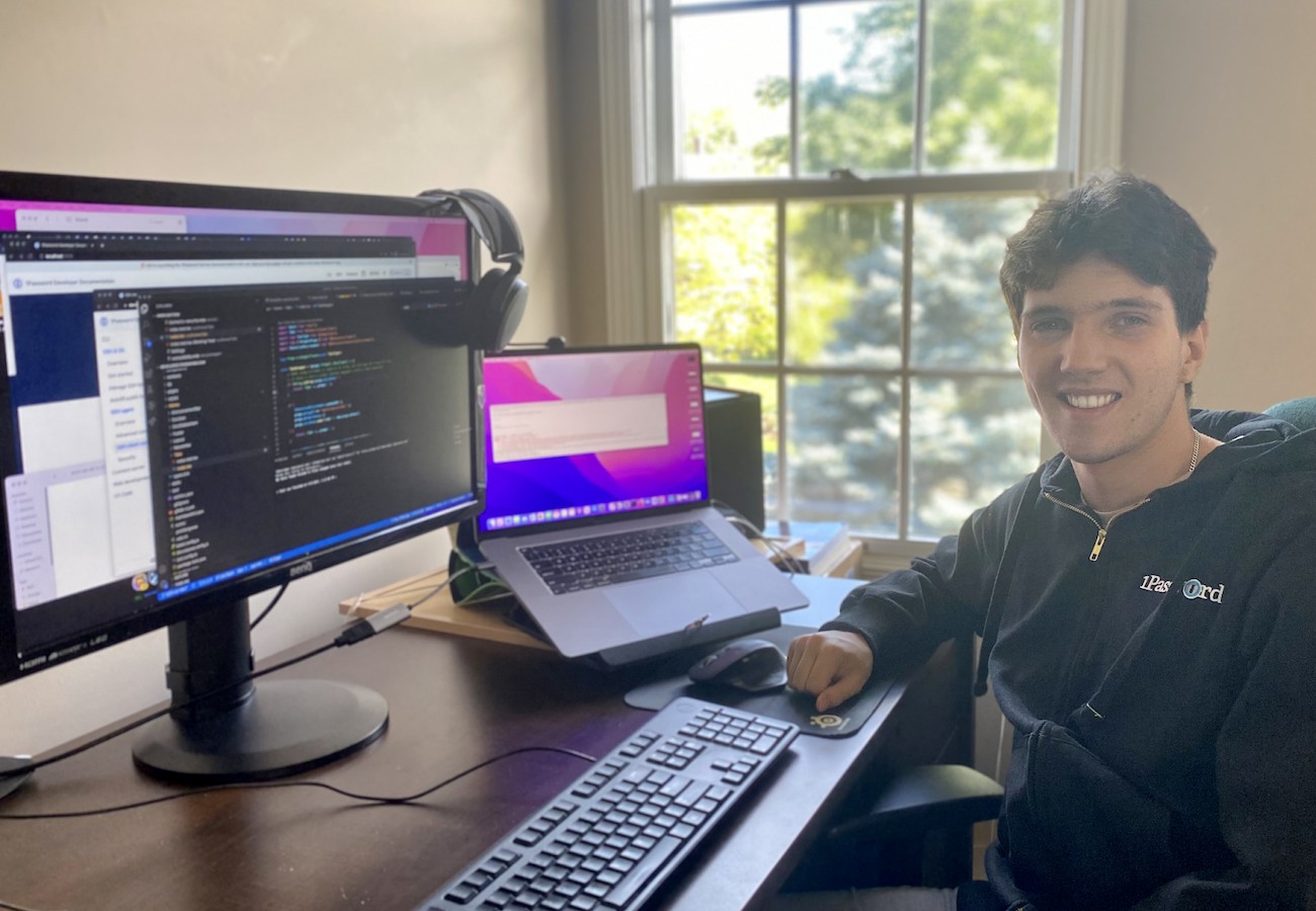 1Password intern Andrew Semchism sitting at his desk with a MacBook and second monitor.