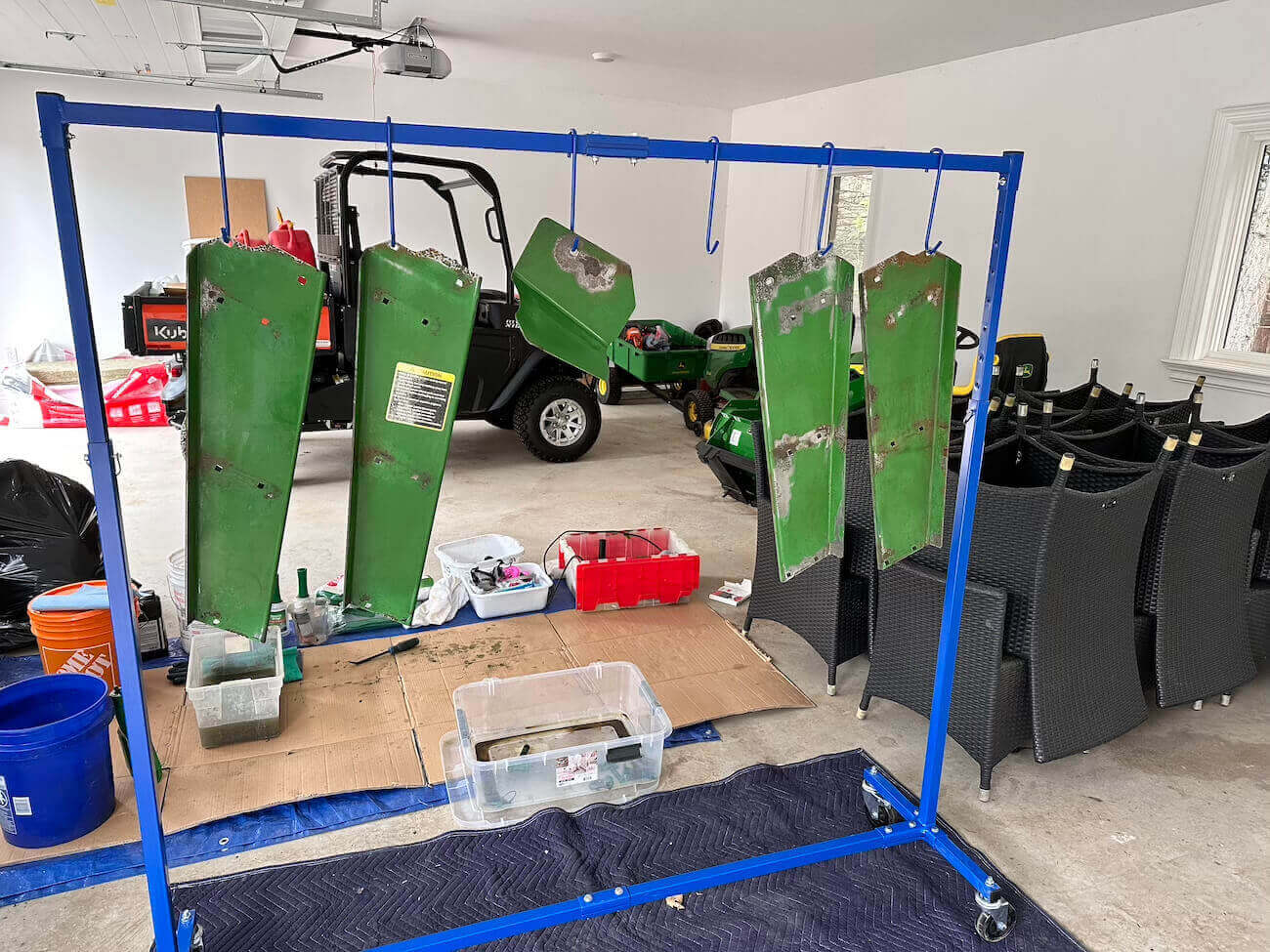 Five tractor parts hanging on a blue rack inside a garage.