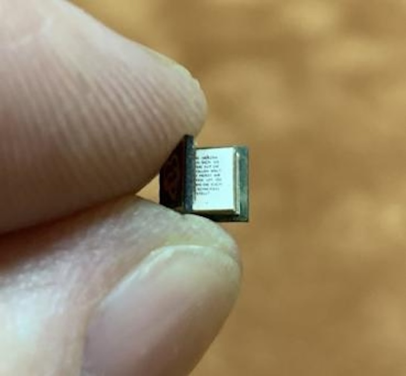 A picture of the tiniest book in the world, which is much smaller than the fingernails of the hand holding it.