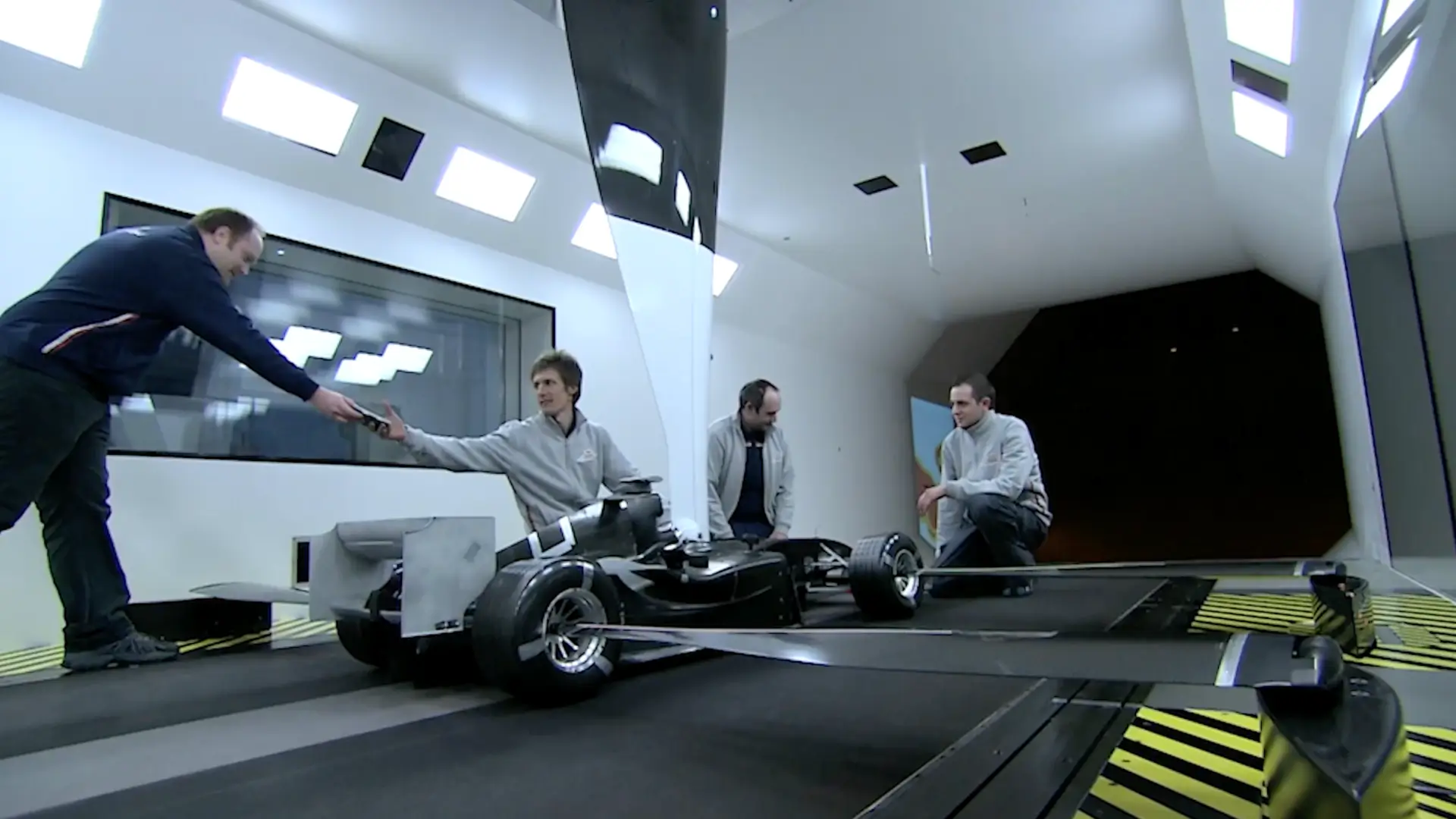 Four Oracle Red Bull Racing engineers test aerodynamics on a miniature racing machine.