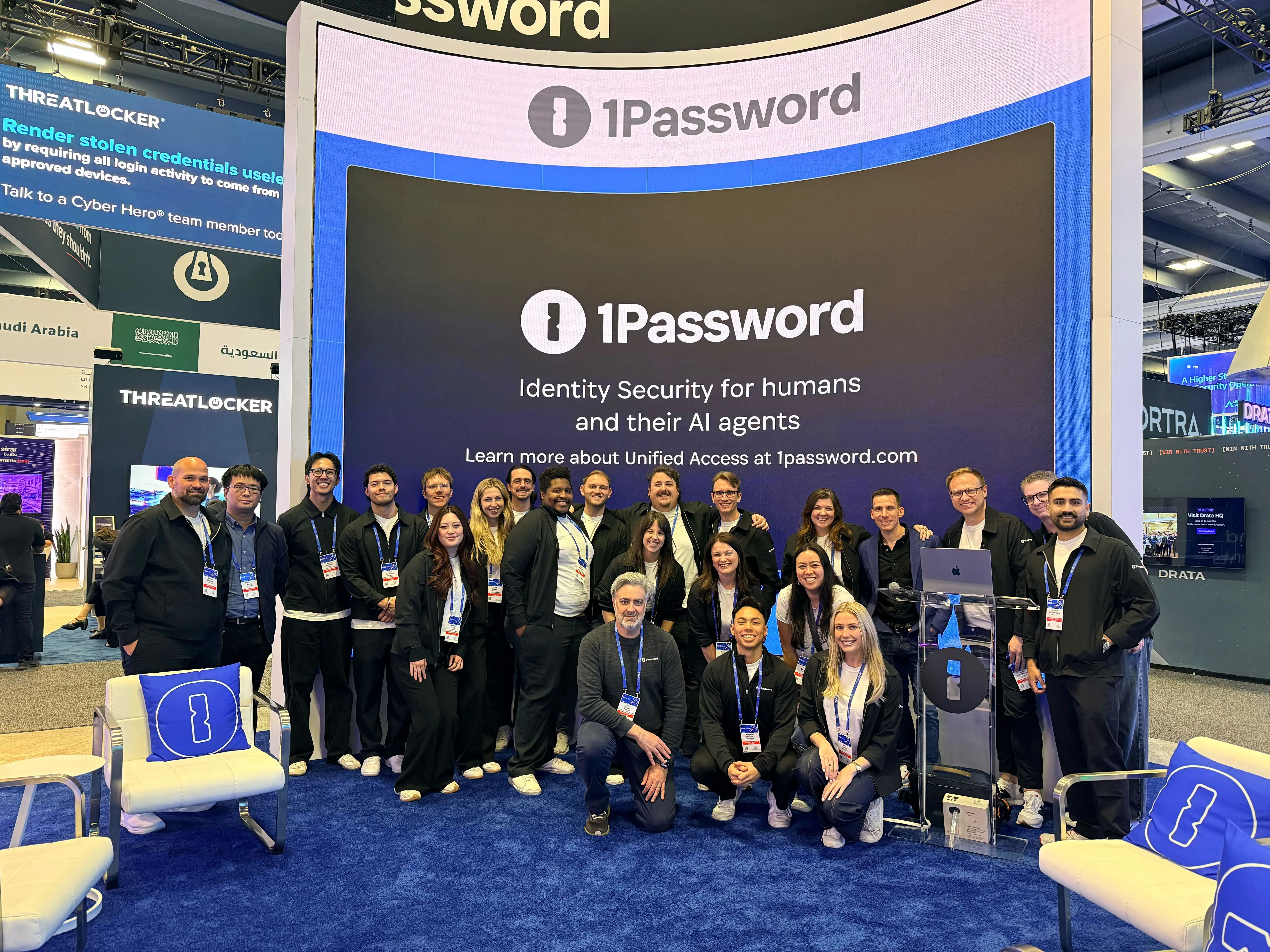 A group of 1Password employees smiling in front of the company's booth at RSAC.