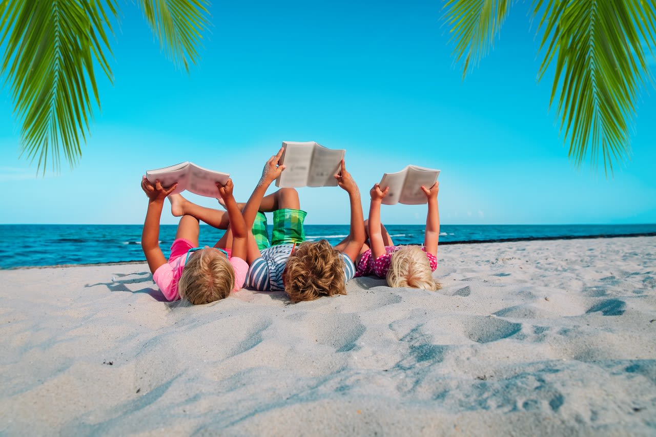 Barn leser en bok på stranden.  Foto: Adobe Stock / nadezhda1906