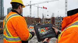Construction safety officer reviewing AI safety analytics on a tablet at a Canadian construction site with cranes.