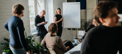 The design team in a conference room, and one person is giving a presentation, using a flipchart.