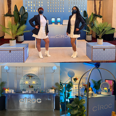 there are two women in white dresses and black jackets standing in front of a display
