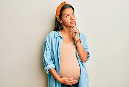 mulher grávida segurando a barriga enquanto pensa