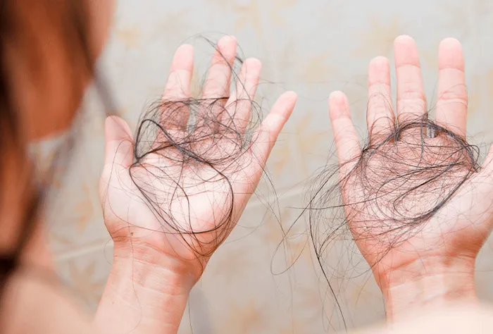 uma mulher segurando fios soltos de cabelo com as duas mãos