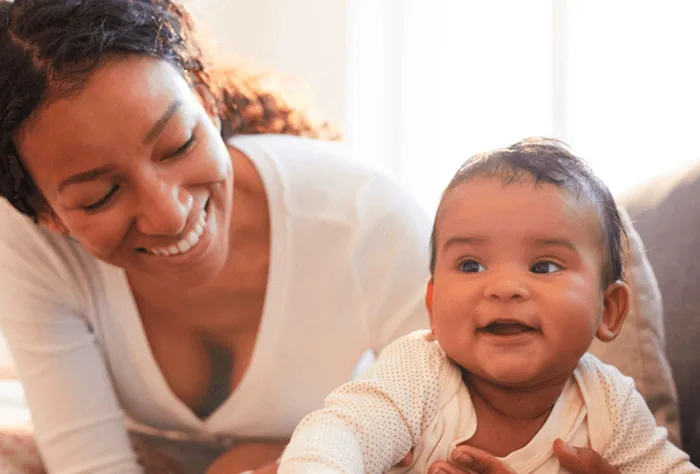 mulher sorridente segurando seu filho na cama