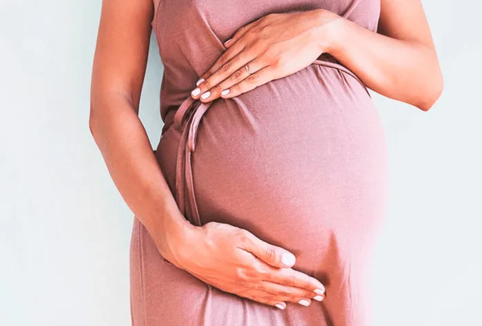mulher grávida segurando a barriga com as duas mãos