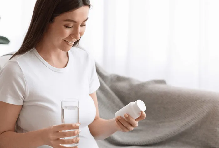 mulher grávida tomando comprimidos com água