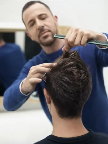 Fryzjer podcina włosy mężczyźnie.