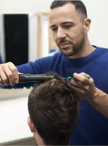 Fryzjer podcina włosy mężczyźnie.