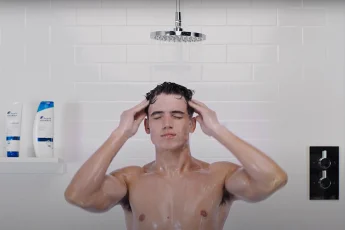 Mężczyzna myje włosy pod prysznicem kosmetykami Head&Shoulders.