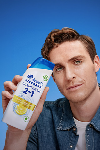 Mężczyzna trzyma butelkę szamponu H&S Citrus Fresh 2 w 1.