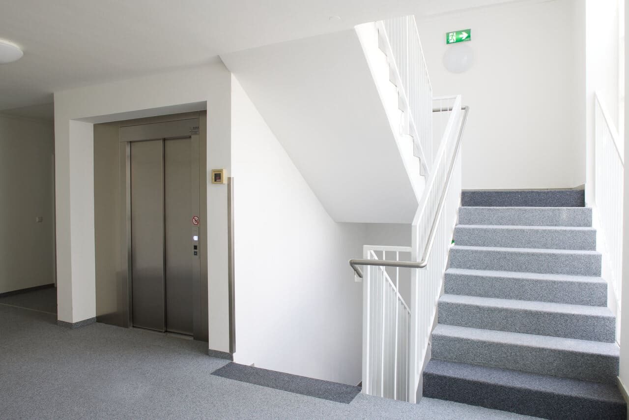 A hallway with a staircase and an elevator door