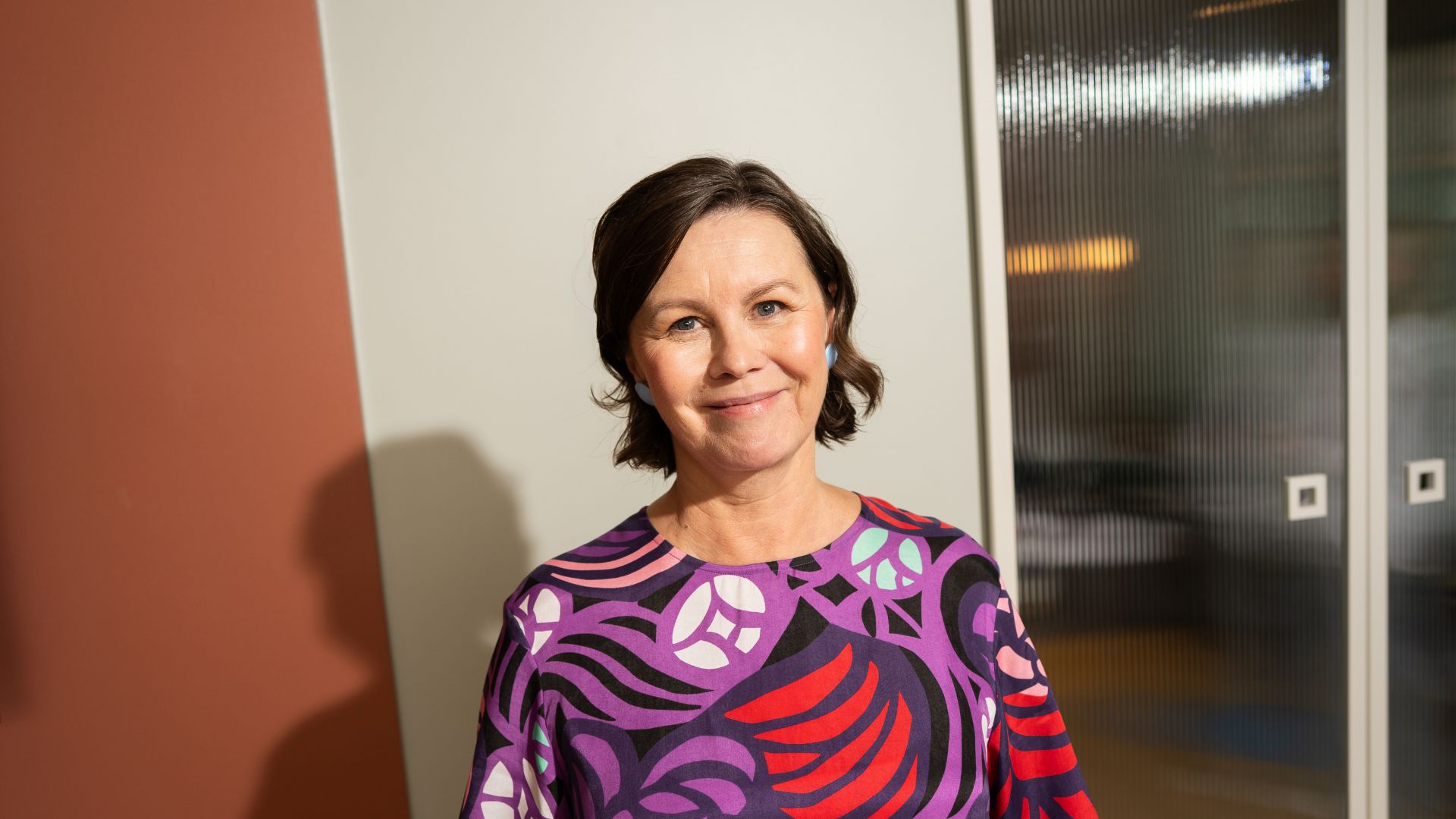 Nainen hymyilee ja katsoo eteenpäin.