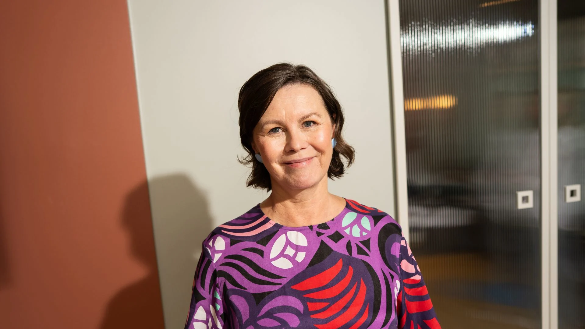 Nainen hymyilee ja katsoo eteenpäin.