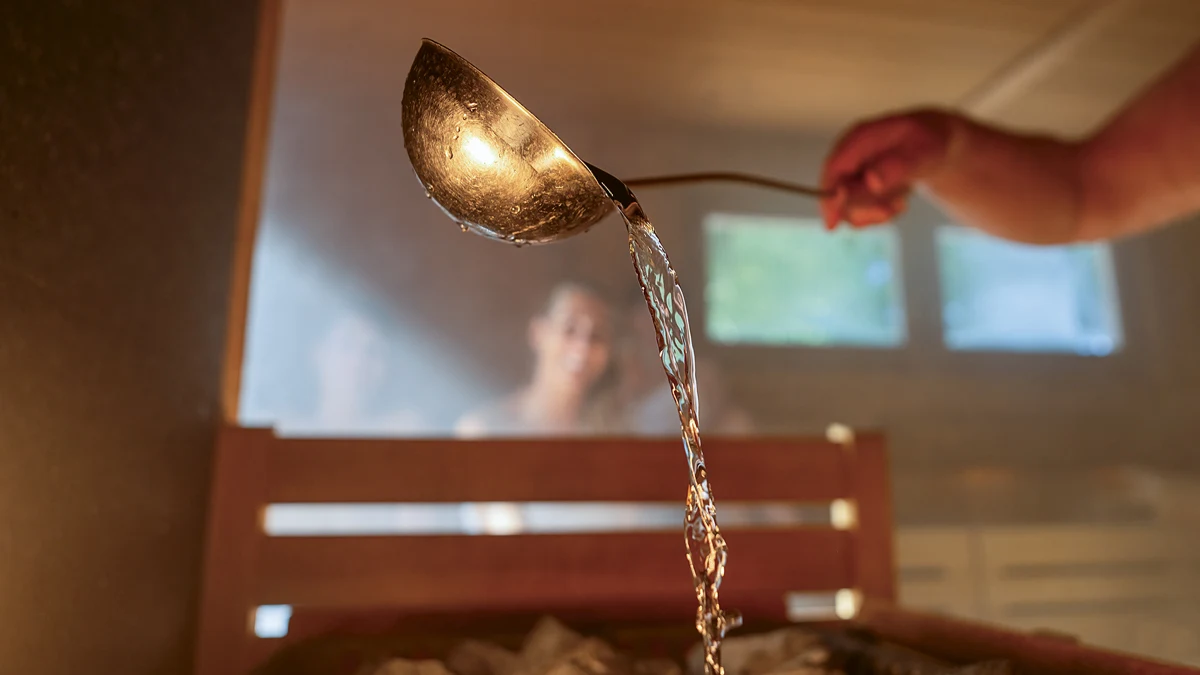 Mies heittää vettä kiukaalle