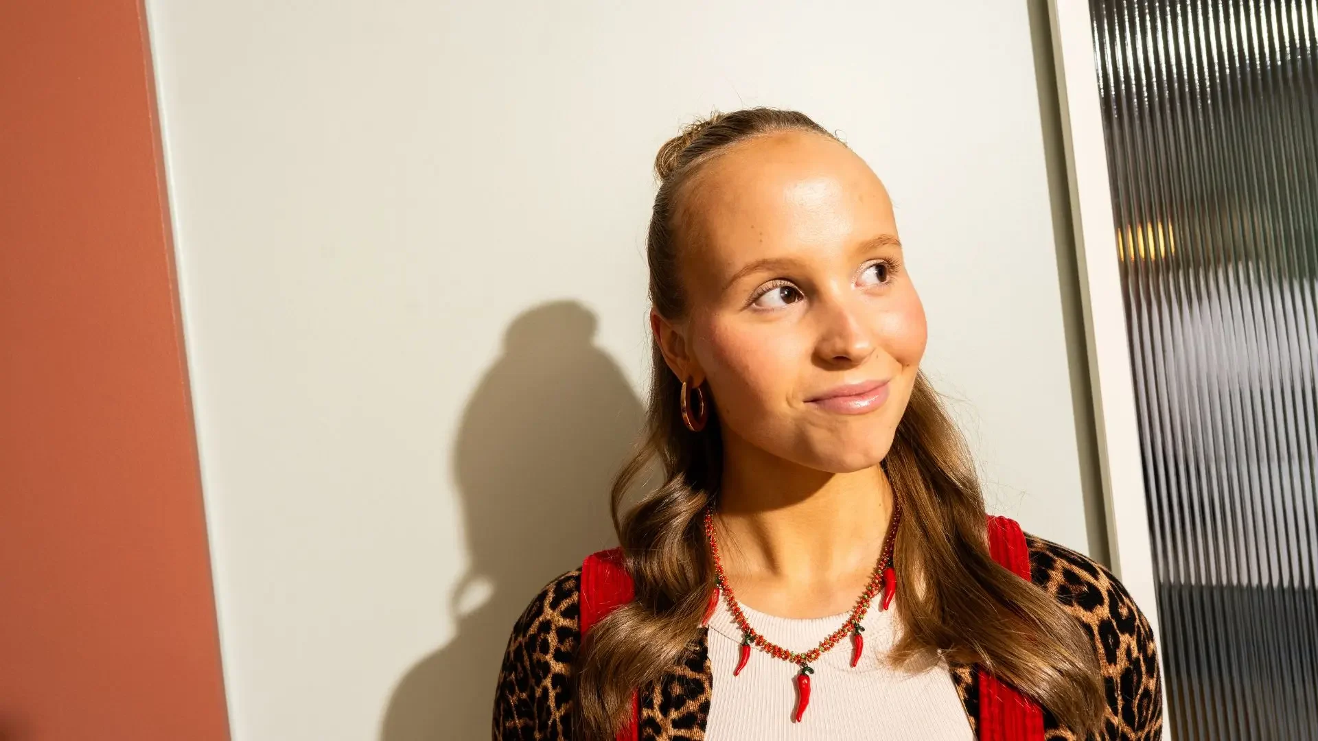 Nainen hymyilee ja katsoo sivulle.